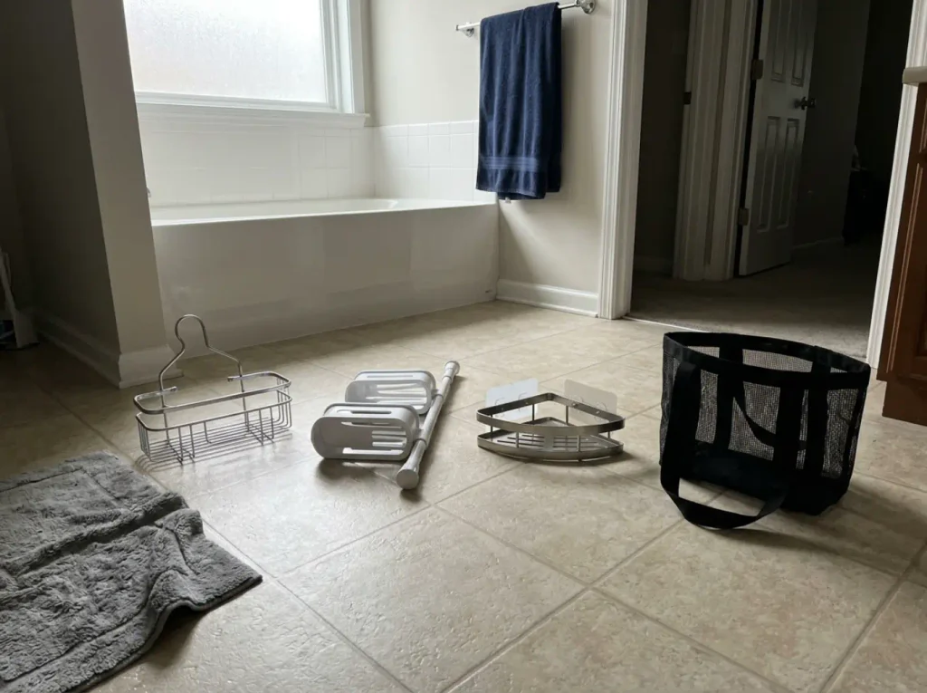 Best Shower Caddies for Renters and Shared Baths 1 Four shower caddy types laid out on a bathroom floor before choosing one for the shower