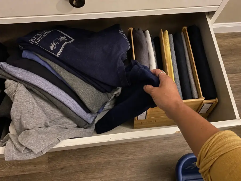 Stacked pile of folded shirts collapsing in a dresser drawer next to upright file-folded rows