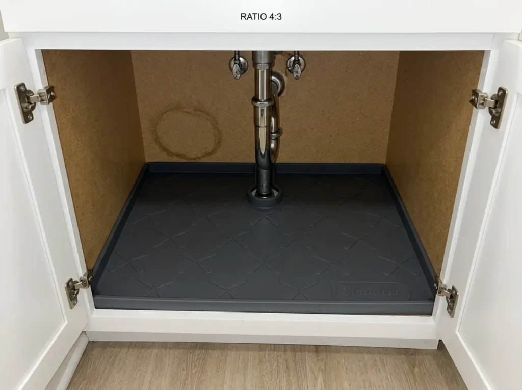 Cleaning Supplies Under the Sink? Store Them Safely 1 Waterproof silicone mat laid across an empty bathroom under-sink cabinet floor before restocking
