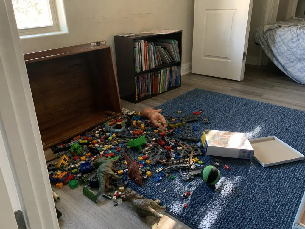 Deep toy box emptied onto the floor of a small bedroom showing why one big bin fails in small spaces