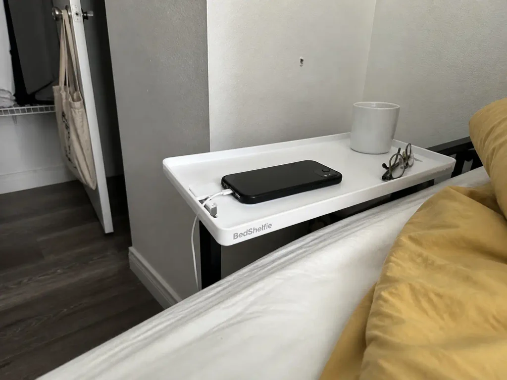 Bed-rail clamp shelf mounted to a bed frame as a no-drill nightstand alternative in a rental