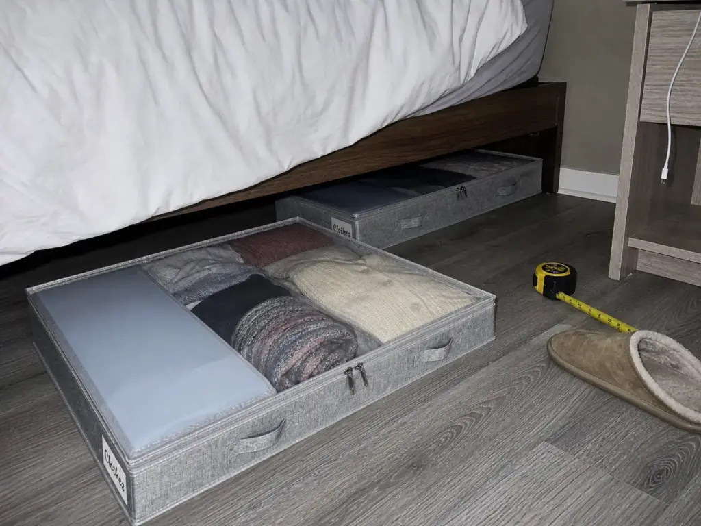 Low profile under bed storage drawer pulled out from beneath a platform bed in a small rental bedroom