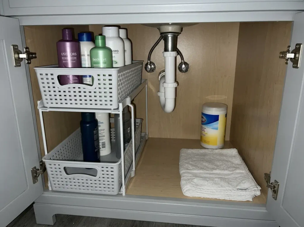 Two-tier pull-out sliding drawer organizer installed under a bathroom sink with the top drawer pulled open