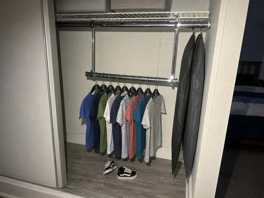 Clip-on double rod hung at kid height with slim velvet hangers in a rental closet