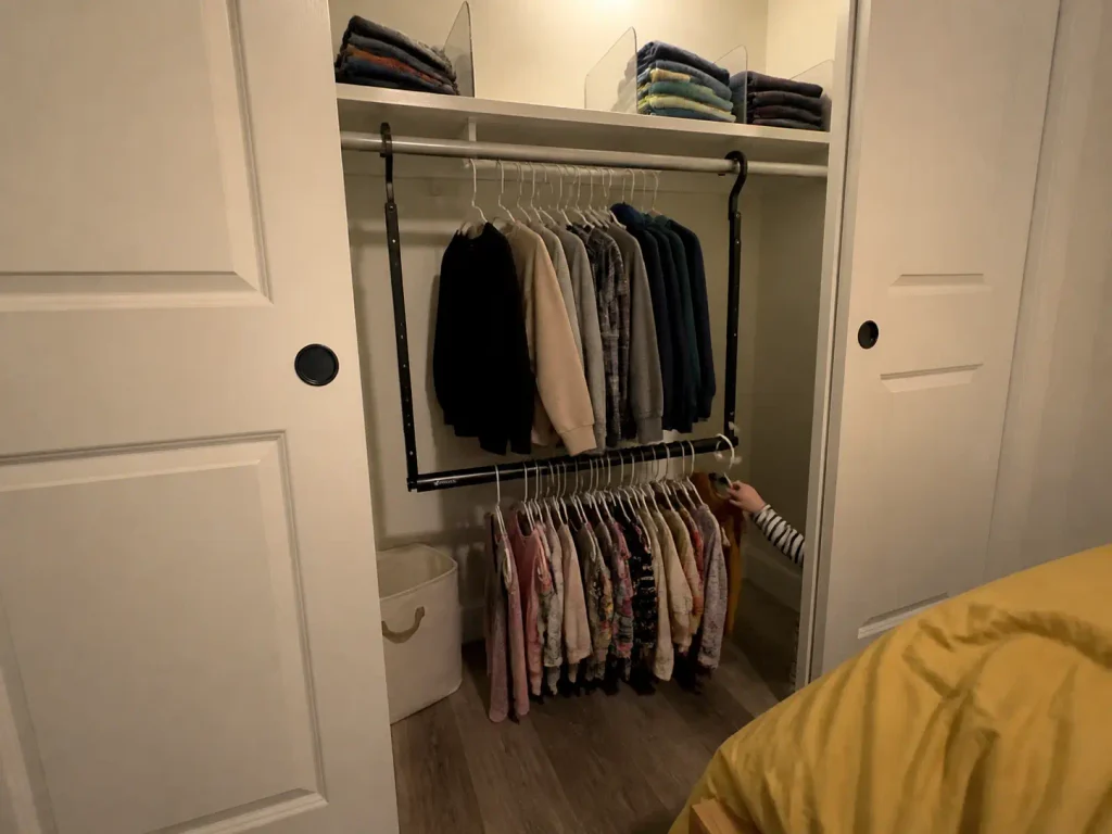 Kids closet with a double rod split by reach height, small clothes on the lower rod and larger above