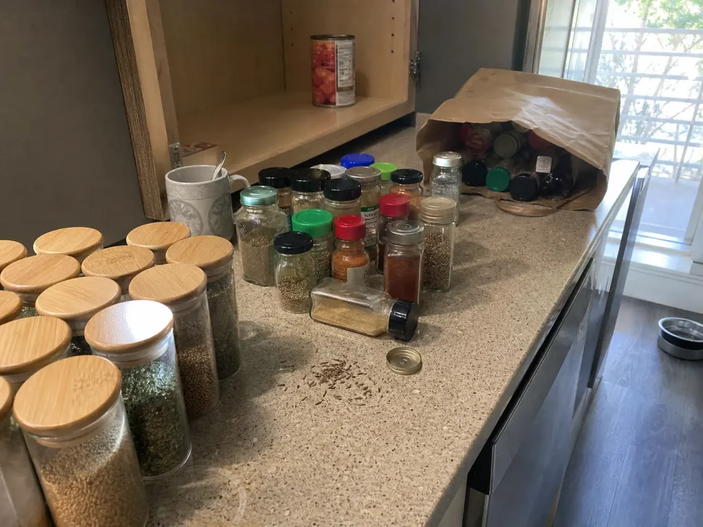 How to Organize Spices in a Small Kitchen Without a Rack 4 Spice jars sorted into keep and discard groups on a small kitchen counter during a purge