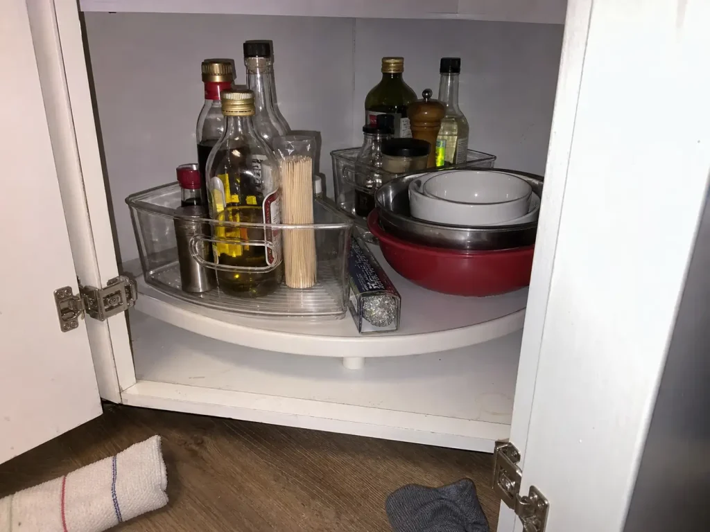 Why Your Small Kitchen With Few Drawers Stays Cluttered 4 Corner base cabinet opened with a wedge lazy Susan bin holding what no longer fits in the kitchen drawers