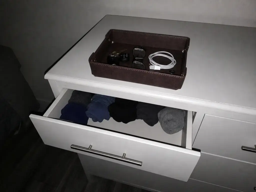 Valet catch-all tray on a dresser top holding keys and small stray items beside a half-open drawer