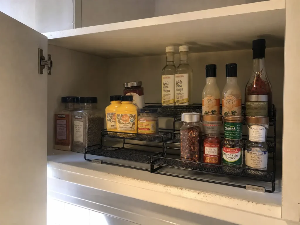 Best Spice Rack Organizers That Actually Stay Put 6 Three-tier expandable spice rack on a cabinet shelf with the back row of jars visible