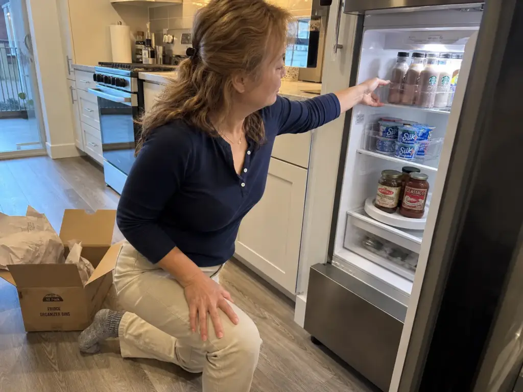 Narrow clear organizer bins fitted onto the shallow shelf of a small apartment fridge