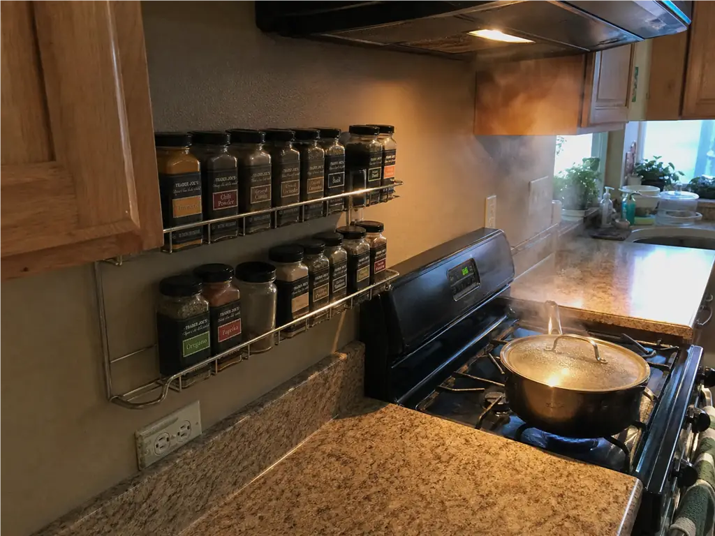 Spice Drawer vs Spice Rack? Your Tape Measure Decides 5 Open spice rack mounted on the wall right beside a stove, where heat and light reach the jars