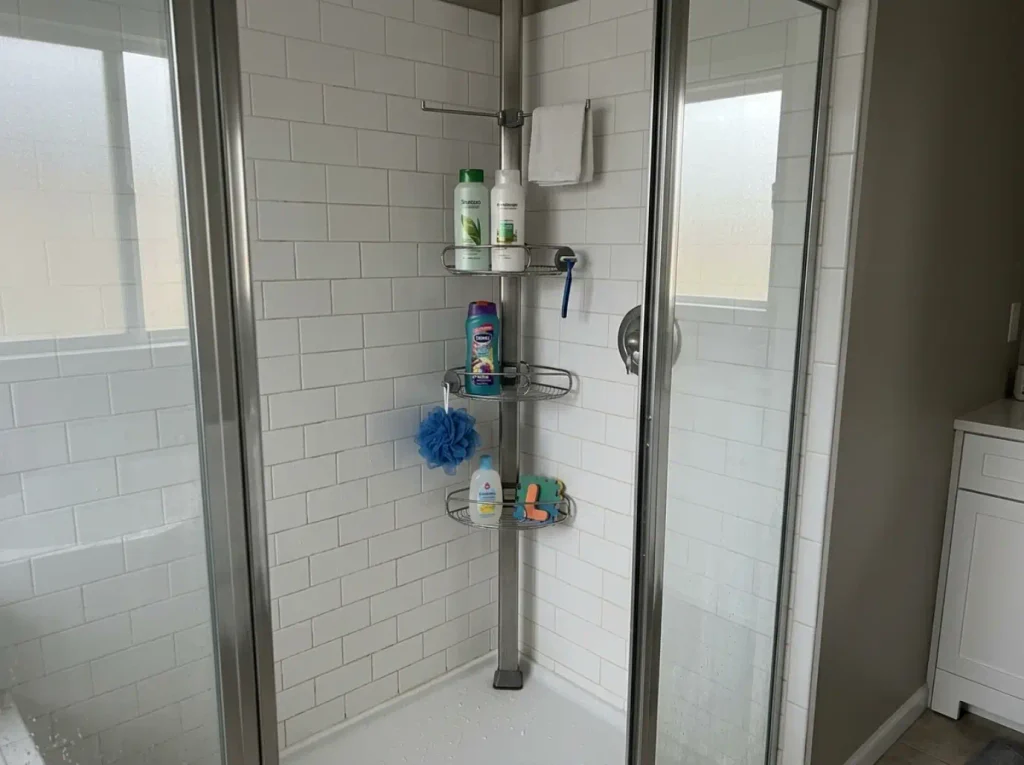 Stainless tension pole shower caddy loaded with a full household's shower products in a corner
