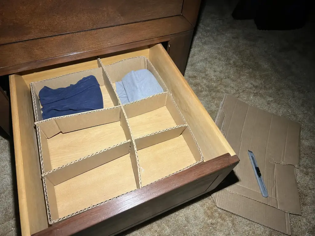 Best Drawer Dividers for Dressers That Actually Fit 11 Hand-cut cardboard divider grid sitting inside a dresser drawer next to a shipping box