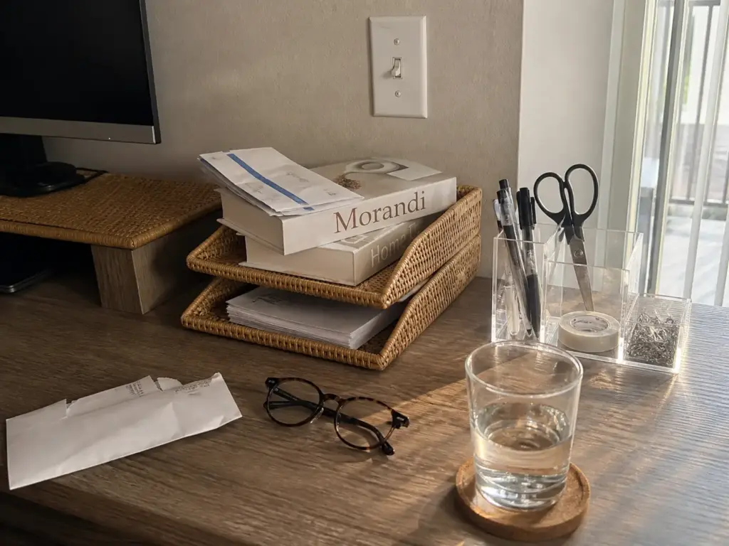 Aesthetic Desk Organization Ideas That Survive Week Two 7 Stacked rattan letter trays sorting mail into inbox and outbox beside a clear pen holder on a desk