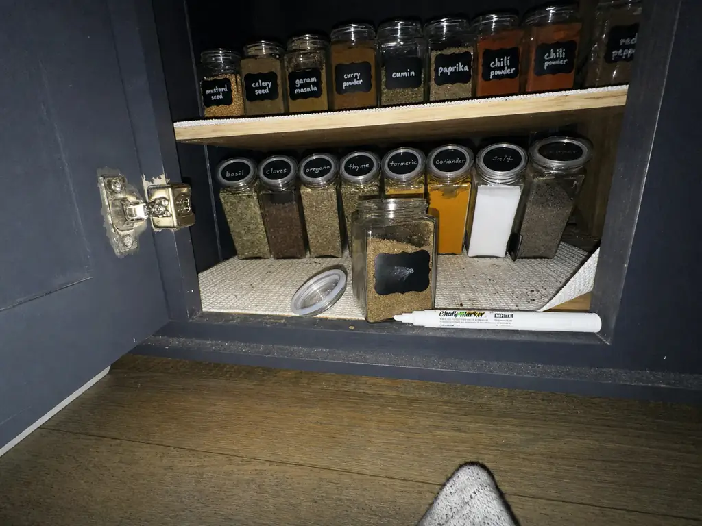 Chalkboard spice labels inside a dark cabinet lit by camera flash showing low-light readability
