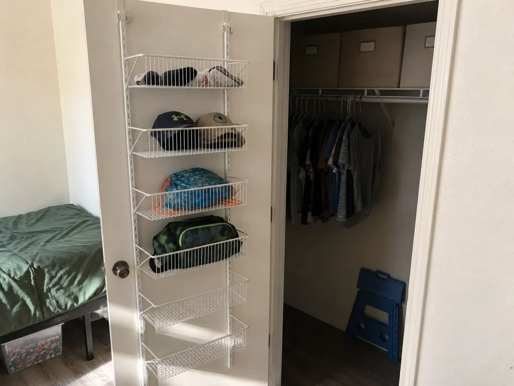 Over-door basket organizer and labeled lidded bins on the top shelf of a kids closet
