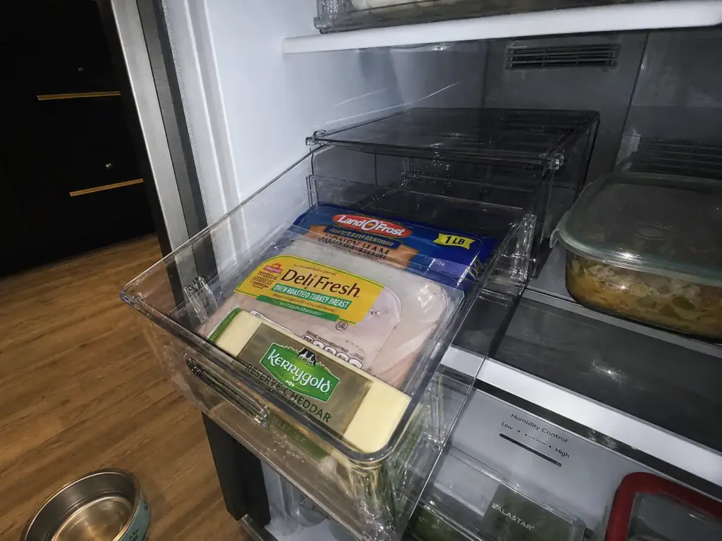 Woman comparing OXO and Heyuzb clear fridge organizer bins at an open refrigerator