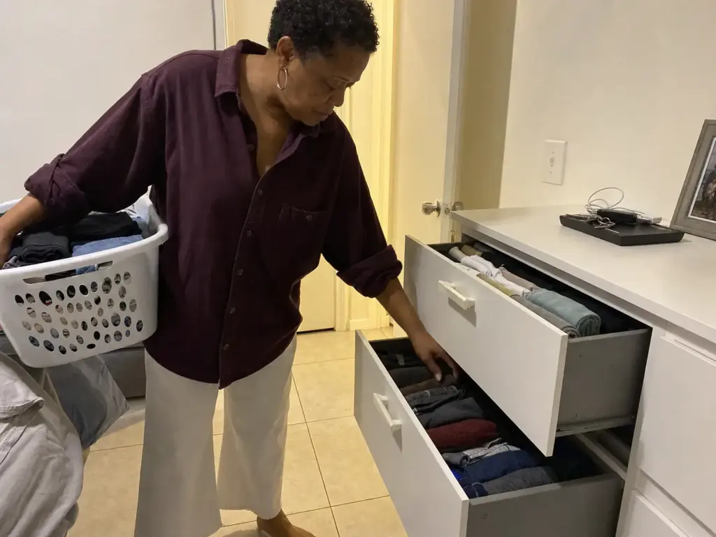 Woman putting laundry away into a shared dresser, doing a quick two-minute drawer reset