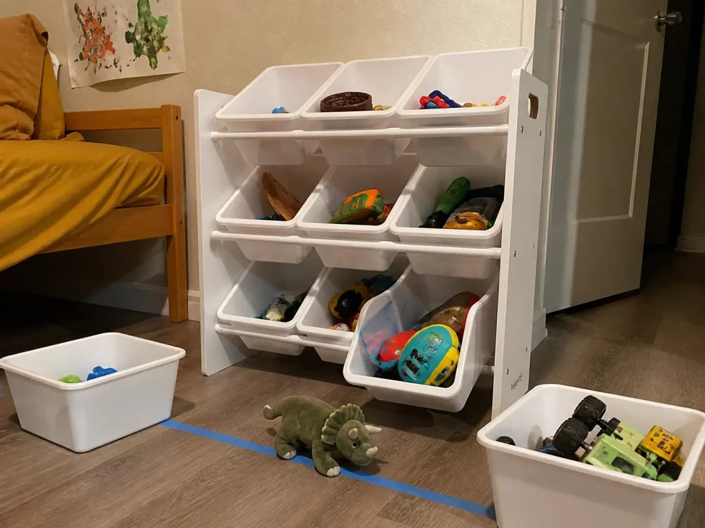 Three-tier toy organizer with removable bins split between a younger and older sibling in a shared room