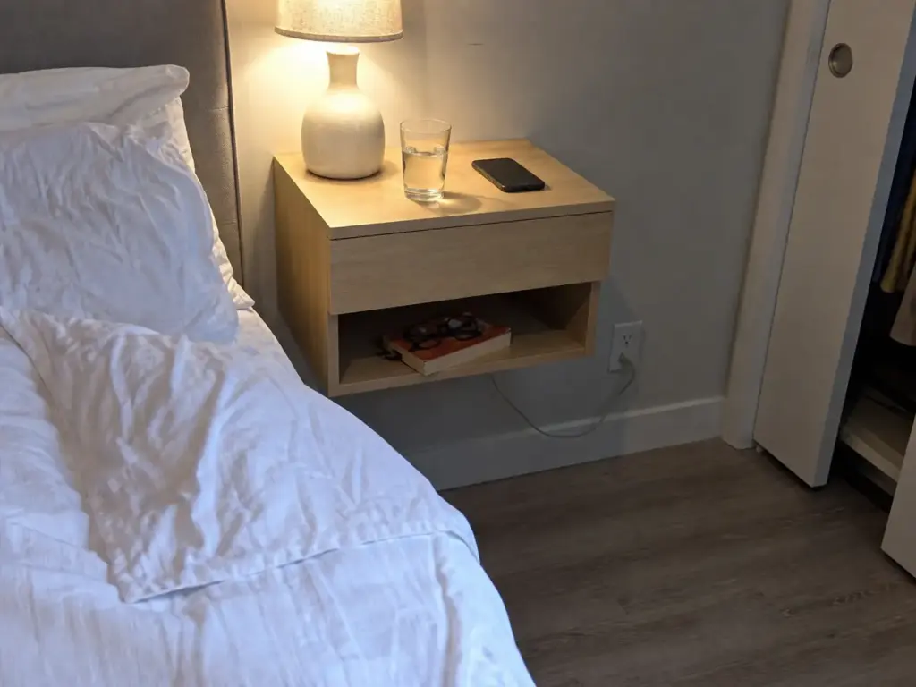 Wall-mounted floating nightstand beside a bed keeping the small bedroom walkway clear