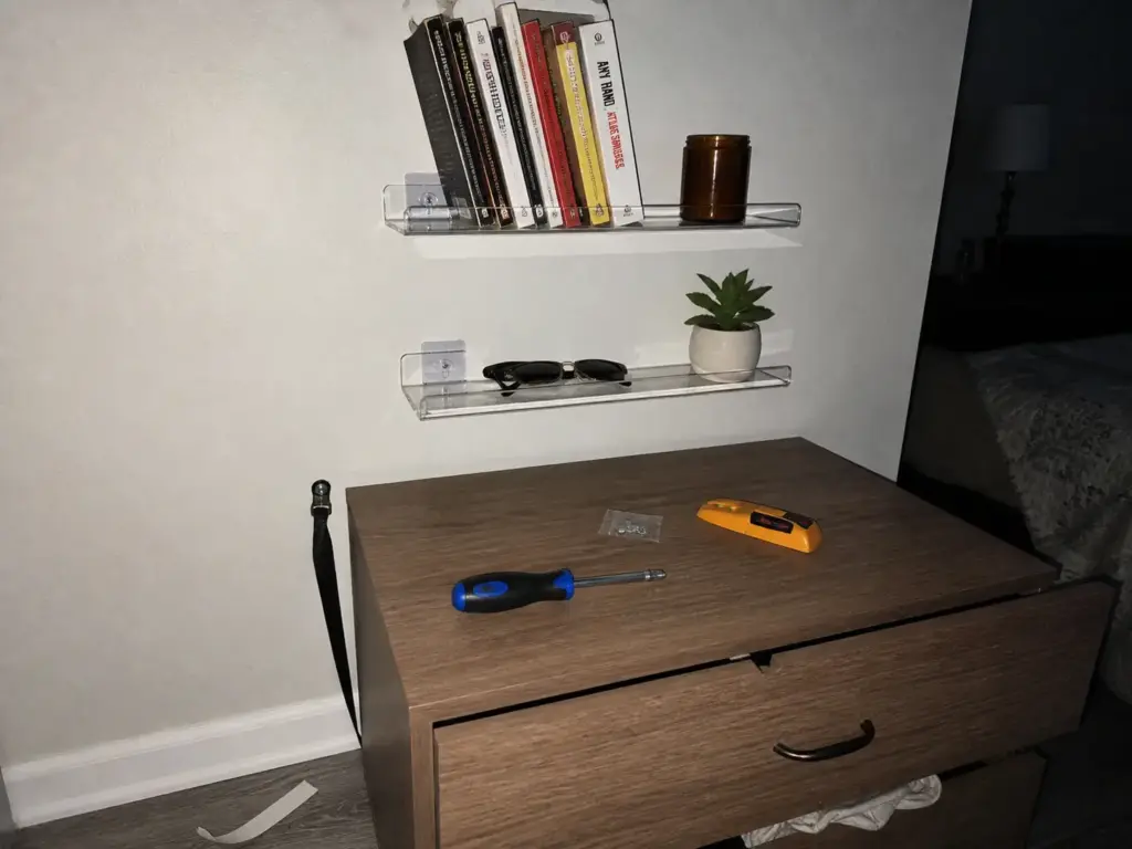 No-drill acrylic wall shelves mounted above a dresser in a small rental bedroom