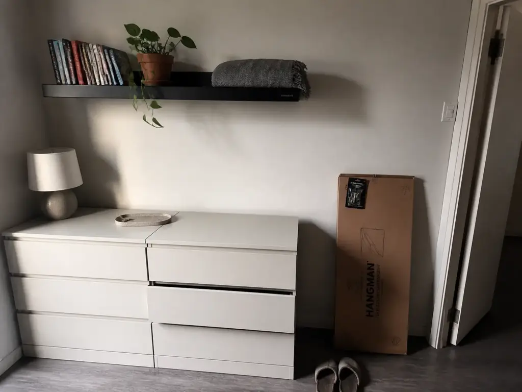 No stud floating shelf mounted above a dresser in a small rental bedroom to keep the floor clear