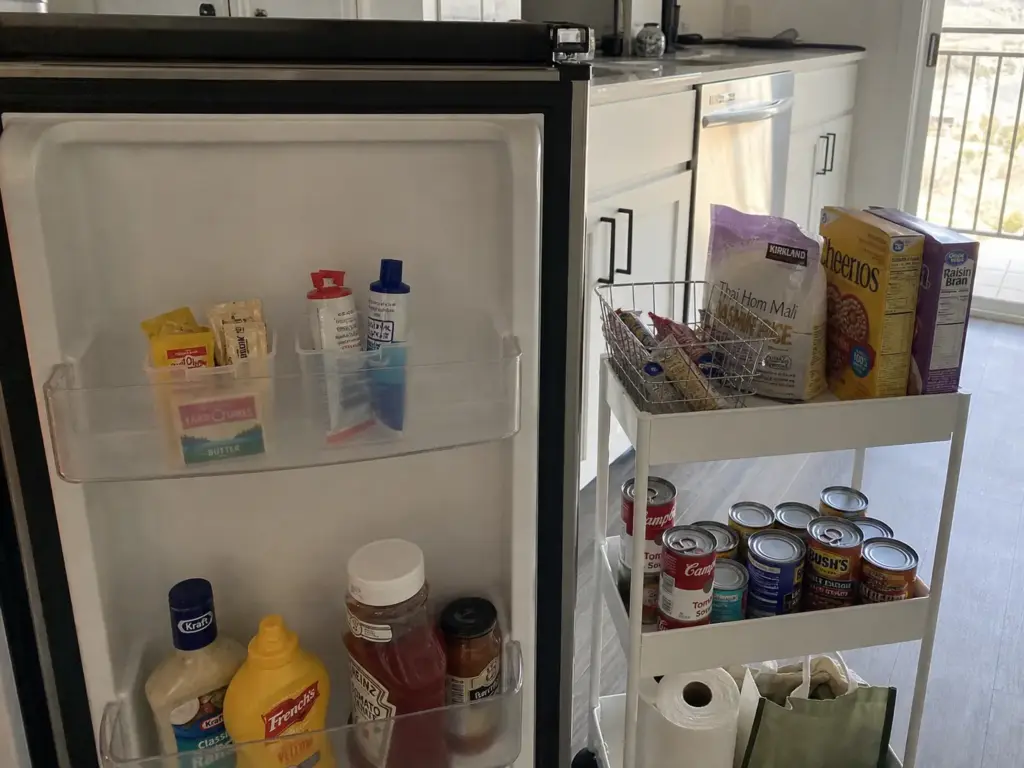 Small fridge door organizer boxes and a rolling cart used as no-drill renter storage