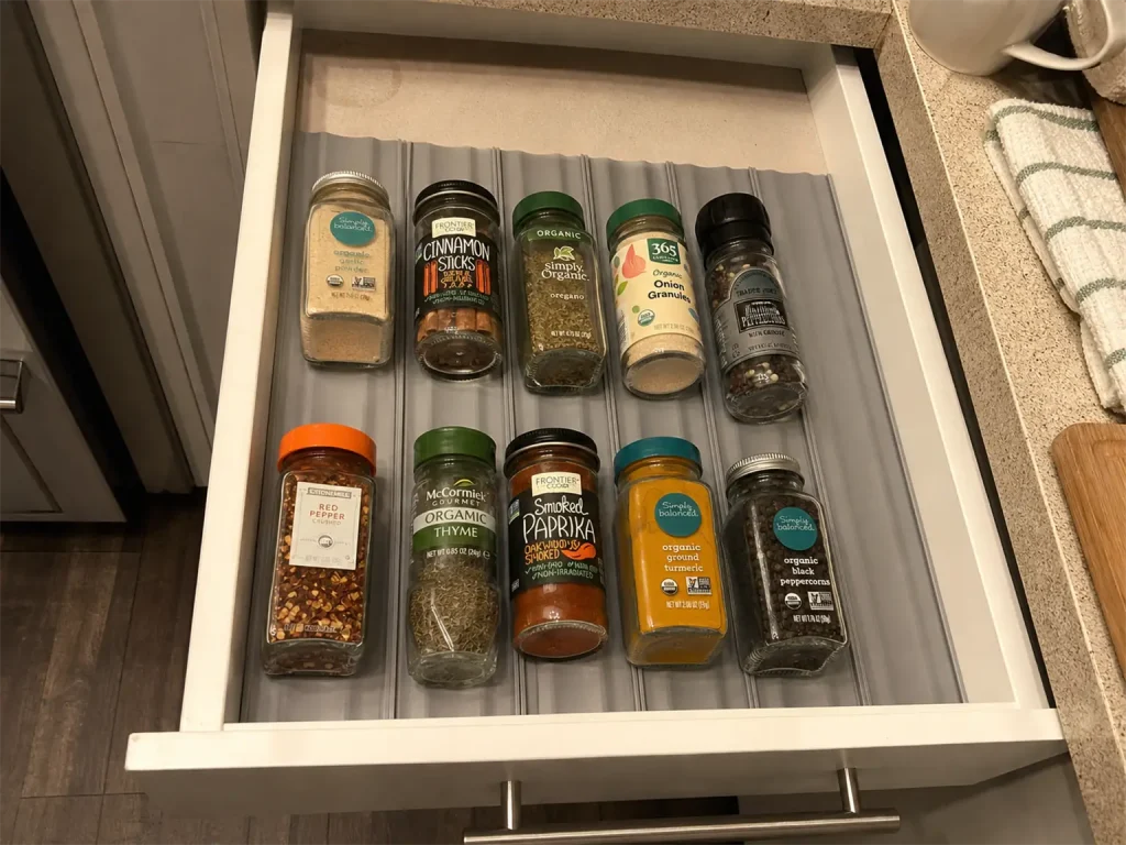 Best Spice Rack Organizers That Actually Stay Put 9 Open kitchen drawer with a spice liner keeping jars from rolling, lids facing up