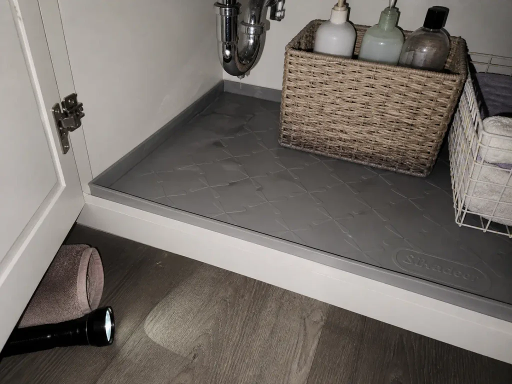 Waterproof silicone under sink mat with raised edges holding water beneath a bathroom P-trap
