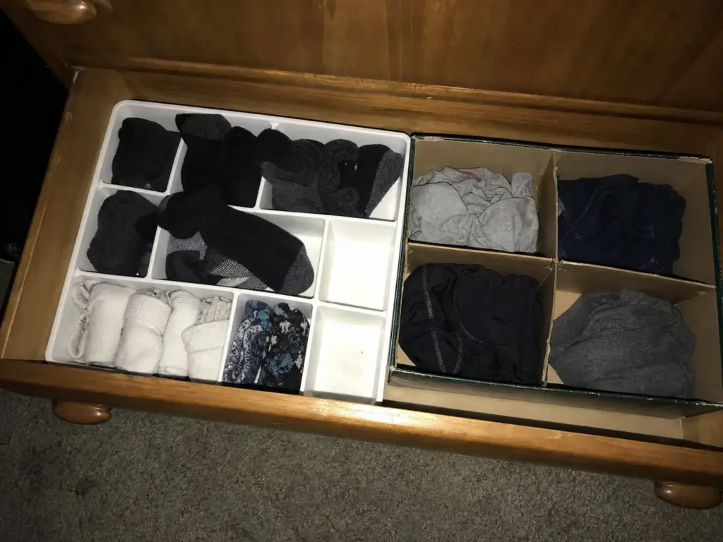 Compartment tray of rolled socks in a dark drawer photographed with direct flash