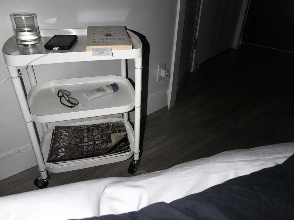 Nightstand alternative photographed at night showing a routed charger cable beside the bed
