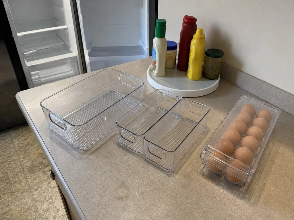 Modular fridge organizer trays and a lidded egg bin arranged on a counter next to a small turntable