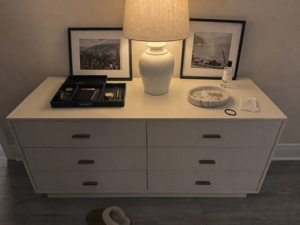 Shared dresser top split into two zones with one valet tray per person and a lamp as divider