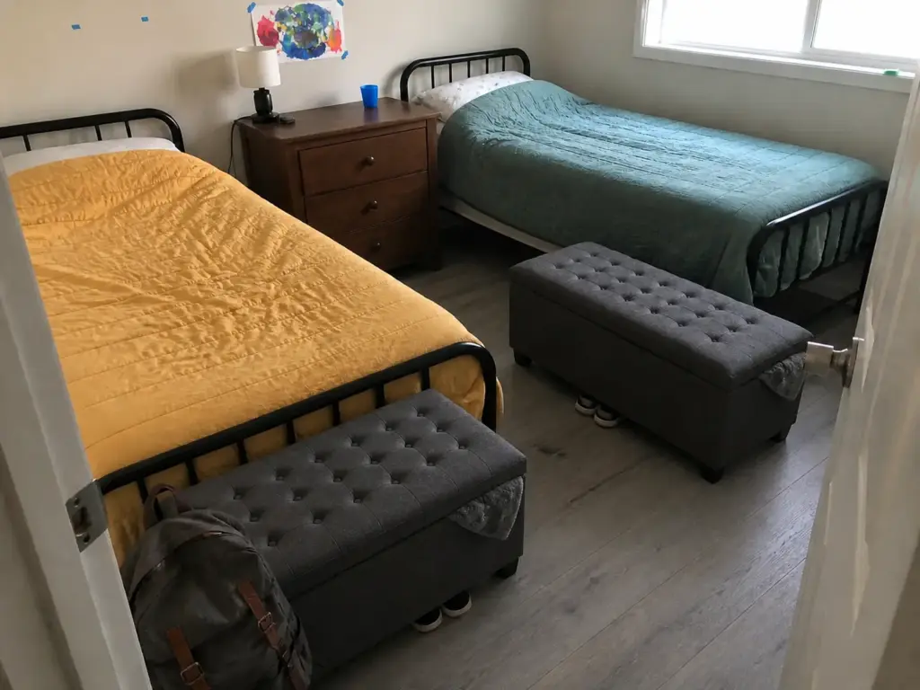 Storage ottoman bench between two twin beds in a shared small bedroom with clear walkways