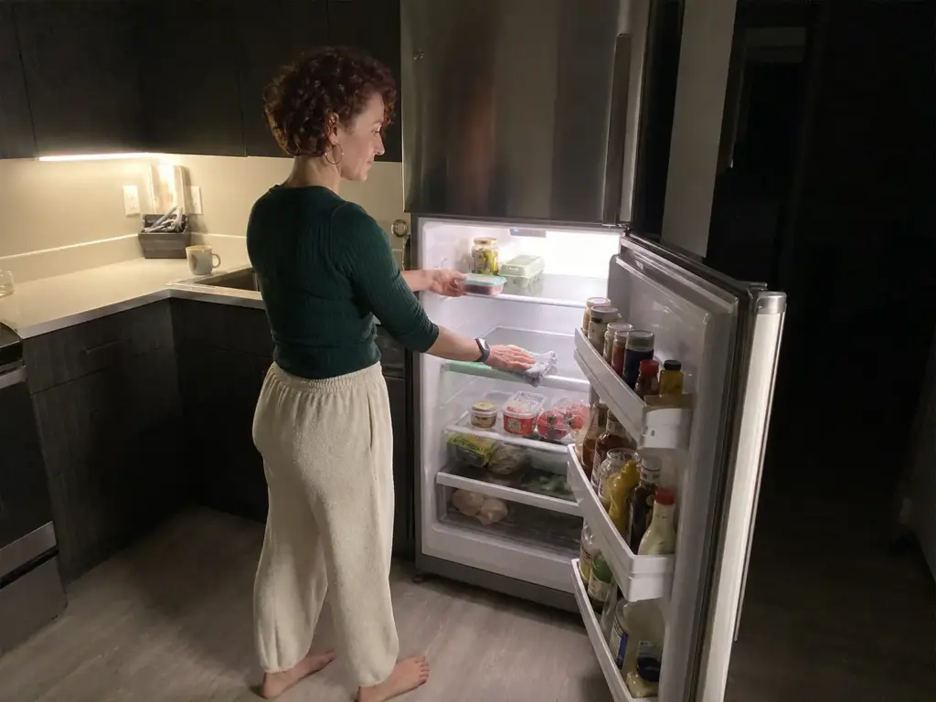 Woman doing a quick weekly reset of a small fridge shelf to keep it organized