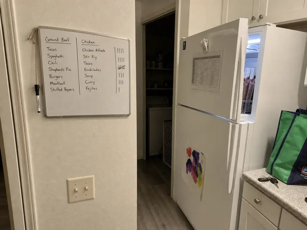 Small dry-erase inventory board beside a freezer with tally marks, the habit that keeps it organized