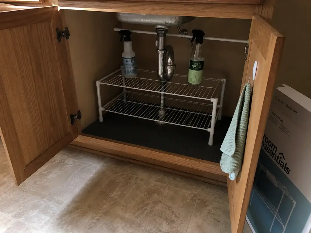 Freestanding no-drill under sink setup in a rental kitchen with a shelf unit resting on the cabinet floor