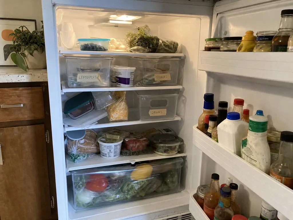 Refrigerator two weeks after organizing with items pushed out of their bins and back onto shelves