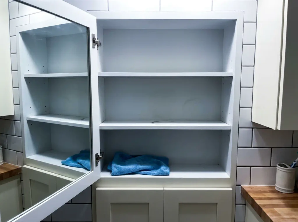 Empty medicine cabinet shelves photographed with flash, everything removed and a cloth on the bottom shelf