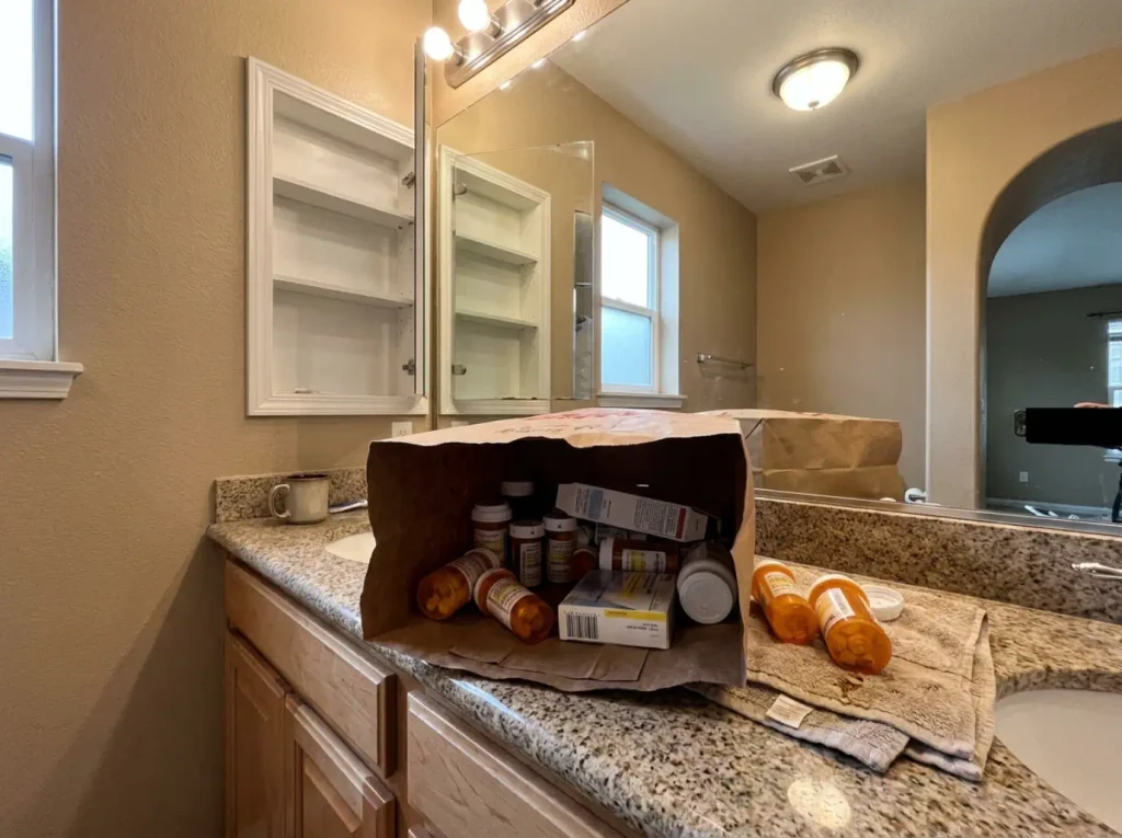 Medicine Cabinet Organization for 3-Inch Shelves 1 Expired medicine bottles gathered in a paper bag on a bathroom counter, ready for a pharmacy take-back drop box