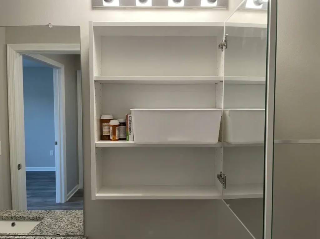Medicine cabinet door caught open on an oversized storage bin that sticks past the shelf edge