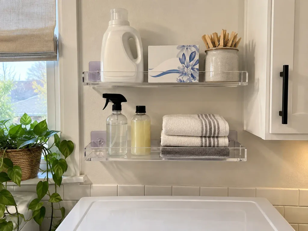 Over Washer and Dryer Storage That Clears the Lid 3 Clear no-drill acrylic wall shelves holding laundry supplies beside a washer in a renovated laundry room