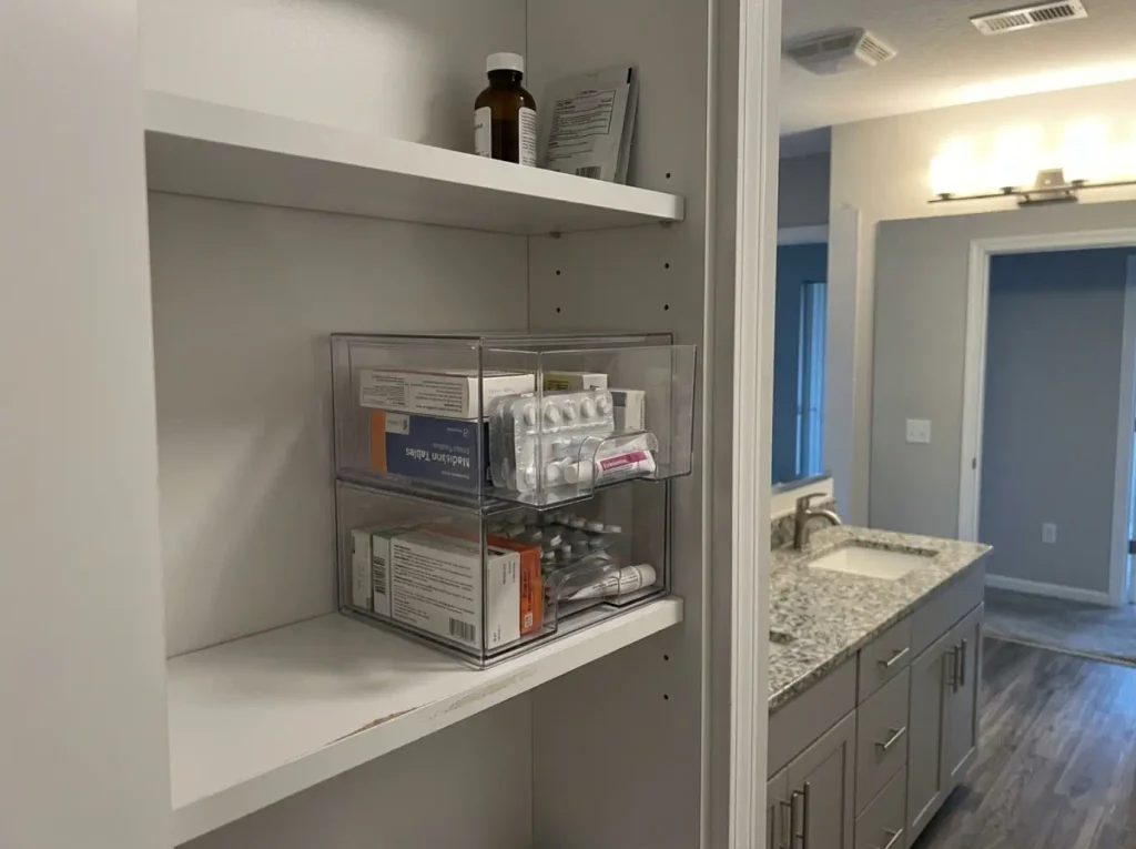 Clear stackable storage drawers stacked two high inside a shallow medicine cabinet shelf
