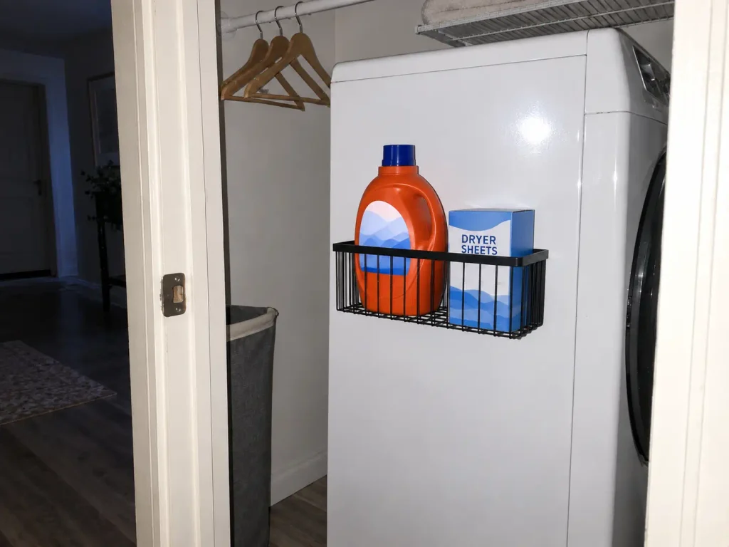 Magnetic organizer shelf holding detergent on the side of a washer in an apartment laundry closet