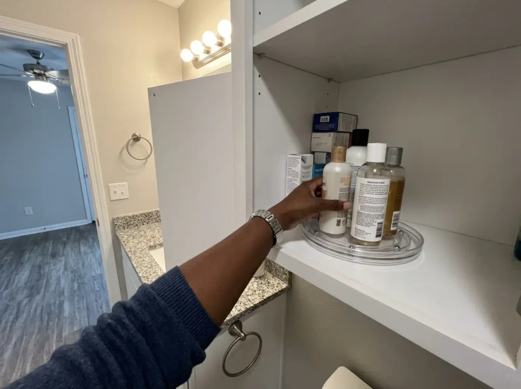 Small acrylic turntable holding round bottles on a shared medicine cabinet shelf