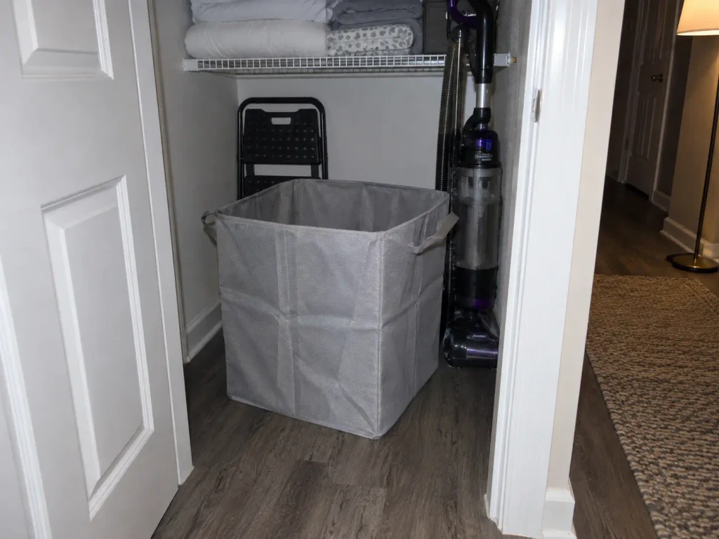 Collapsible laundry basket left standing open in a dark closet corner instead of folded away