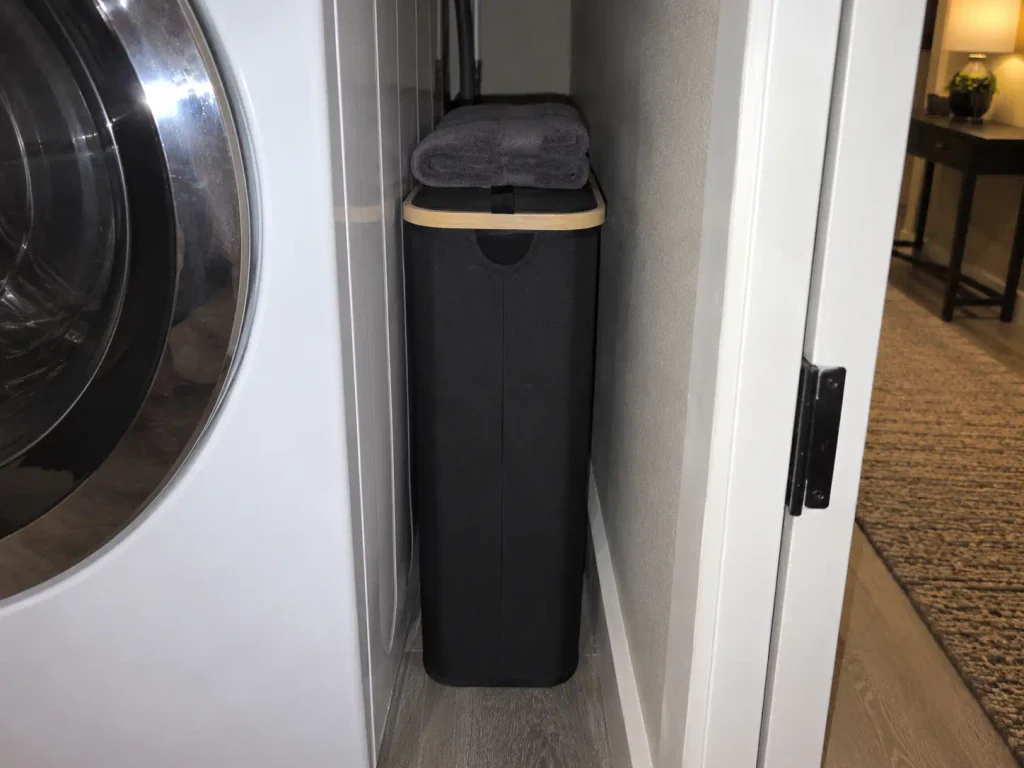 Small Laundry Room Storage for a 29-Inch Closet 11 Slim lidded laundry hamper standing in the narrow gap between a washer and the wall of a laundry closet