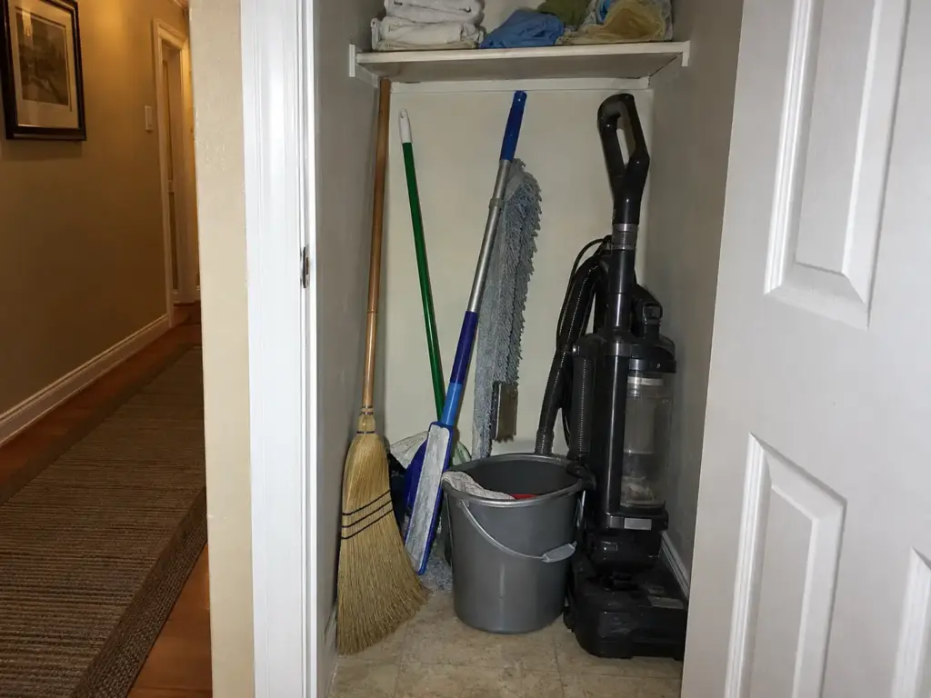 Broom Closet Organization Sized to Your Tallest Handle 1 Inside a broom closet a broom, mop and dust mop lean at different angles with a bucket and vacuum crowding the floor