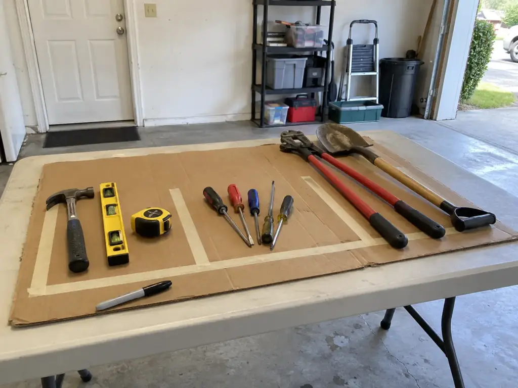 7 Garage Tool Organization Ideas That Fit Each Tool 1 Hand tools sorted into three loose groups on a folding table in a garage before choosing where each one goes