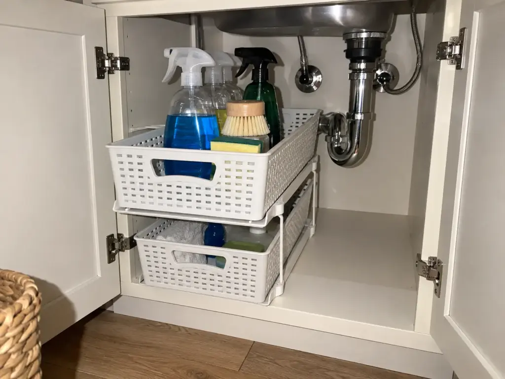 Best Cleaning Supply Organizers for the Space You Have 4 A two-tier pull-out drawer in an open kitchen sink cabinet, the top tier slid halfway out holding bottles and a sponge